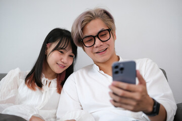 Relax young adult asian lover couple living at home concept. Happy smile people sitting on sofa cozy style indoor on day