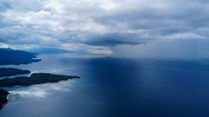 Aerial view of the strait between the islands and rain on the horizon. Rain and thunderclouds over the sea and tropical islands.