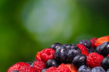 Close-up of juicy blueberries, strawberries, raspberries on a green blurred background. Colorful background of berries, summer food.