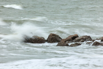 Long exposure shot of the sea showing movement of water over rocks and waves splashing, smooth silky water, rocks stationary, water moving