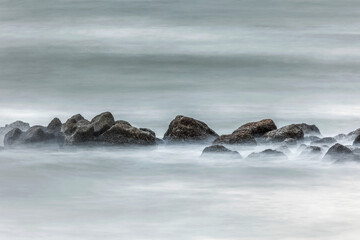 Long exposure shot of the sea showing movement of water over rocks and waves splashing, smooth silky water, rocks stationary, water moving