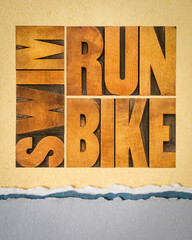run, bike, swim - triathlon concept,  word abstract in vintage letterpress wood type on art paper, sport and recreation concept
