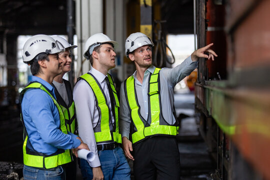 Team railway engineer Inspect repair project train diesel engine in maintenance center. Technician discuss planning checking vehicle and railroad systems.