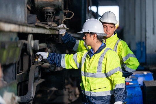Team railway engineer Inspect repair project train diesel engine in maintenance center. Technician discuss planning checking vehicle and railroad systems.