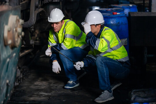 Team railway engineer Inspect repair project train diesel engine in maintenance center. Technician discuss planning checking vehicle and railroad systems.