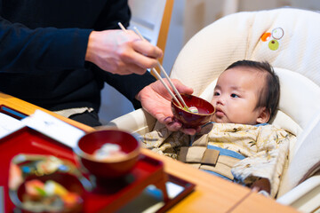 生後100日のお食い初めでパパにもらうご飯を不思議そうに見つめる生後3か月の赤ちゃん