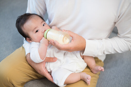 パパに抱っこされておいしそうにミルクを飲む生後3か月の生まれたての赤ちゃん	