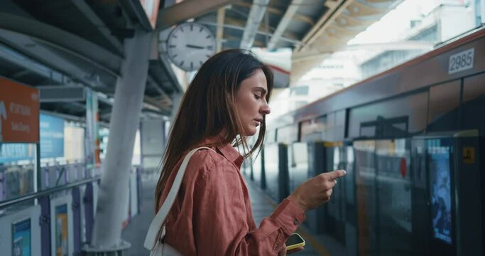 missed the train concept. Woman got the train schedule wrong or missed the train. Young female missed the train , passed by side view looks on a schedule leaving and regrets.