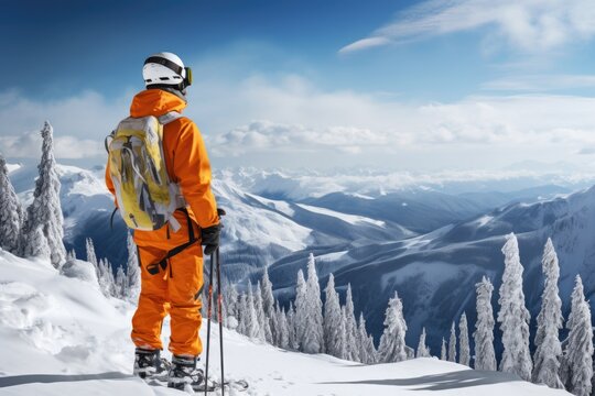 A man wearing an orange suit standing proudly on top of a snow-covered mountain. This image can be used to represent adventure, exploration, and conquering challenges.