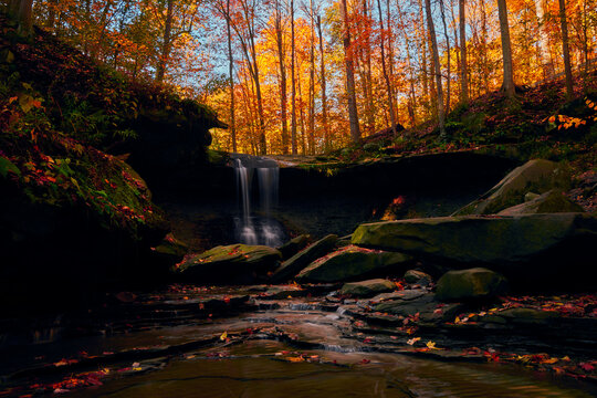 A Waterfall sits within a gorgeous, Autumn colored forest. 