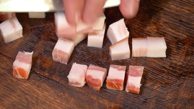 Slicing of salted pork fatback on cutting board, close-up. Ukrainian traditional food - salo	