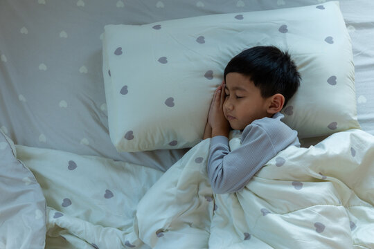 Asian Boy Restful Moment, A Healthy Slumber Amidst Soft Sheets