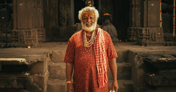 Portrait of a Senior Hindu Monk Looking at the Camera and Smiling in an Ancient Temple. Friendly Indian Senior Man Posing as he is seeking Guidance and Wisdom from his Religion