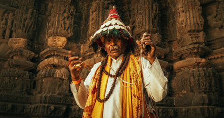 Authentic Portrait of an Old Indian Man in Traditional Attire Playing Instruments and Chanting in...