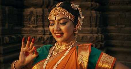 Close-Up of an Indian Female Dancer Displaying Symbolic Gesture with Expressive Face, Using Folkloric Dance to Tell a Story. Girl in Traditional Sari Showcasing the Art of Mudras Movement - obrazy, fototapety, plakaty