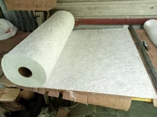 Roll of fiberglass, the material for making fiberglass boats, placed on a wooden table in the...