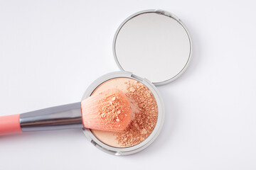 Beautiful eyeshadow palette on white with crushed sample and makeup brush. Makeup product