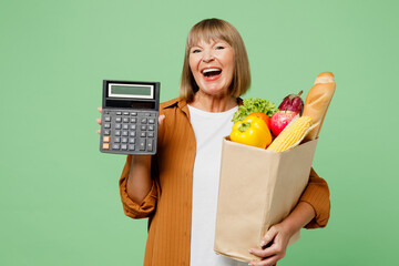 Elderly cheerful happy smiling fun woman wear brown shirt casual clothes hold in hand calculator...