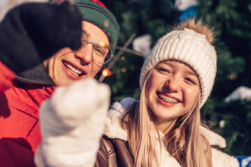 Young couple in love have fun, active date in winter on Christmas Eve.Laughing teenagers light...