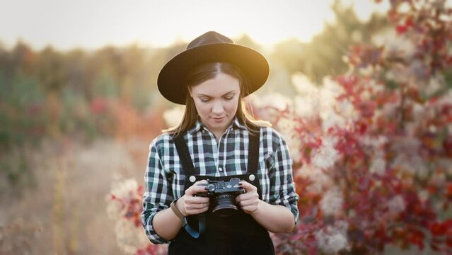 Woman checking pictures on analog digital photo camera on autumn background