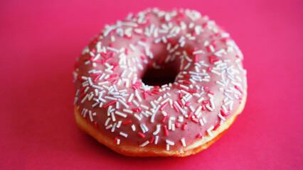 doughnut with icing and powder on a pink background