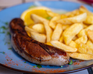 Fried fries potatoes with grilled meat German sausage served in old restaurant in Germany