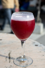 Famous fresh brewed red lambic kriek cherry beer served outside in Belgian beer festival in Durbuy,  special Belgian beer glass in sun lights