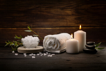wellness spa. body skin care items on dark wooden table. towel, bath crystals, massage stones and...