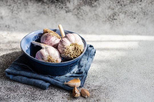 Close-up of fresh garlic bulbs and garlic cloves in a bowl with a napkin