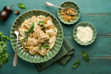 Homemade italian ravioli pasta in heart shape with beef meat, cheese sauce, caramelized onions, basil and saffron on old wooden blue background. Food cooking menu ingredients background. Top view.