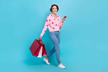 Full body photo of young funny woman bob brown hair walking with phone eshopping promo clothes purchase isolated over blue color background