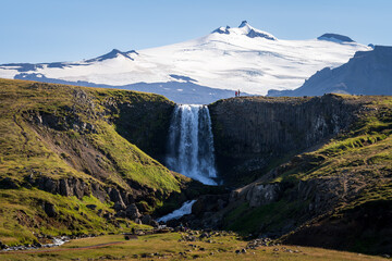 Scenic view of Svodufoss waterfall and Snaefellsjokull glacier in background, Iceland - obrazy, fototapety, plakaty