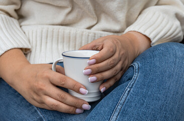 Close-up of a woman sitting down holding a hot drink