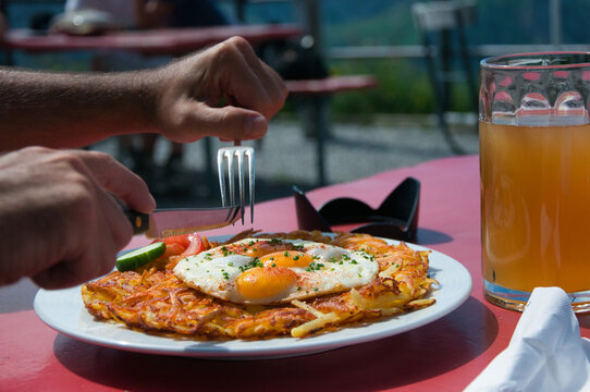 Close-up of a man eating a rosti and fried egg meal with a glass of beer