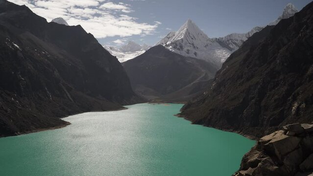 beautiful turquoise water of the lake at laguna paron lagoon in the high andes mountains of the cordillera blanca at huascaran, Peru, with snow covered mountain peaks on a bright sunny day.