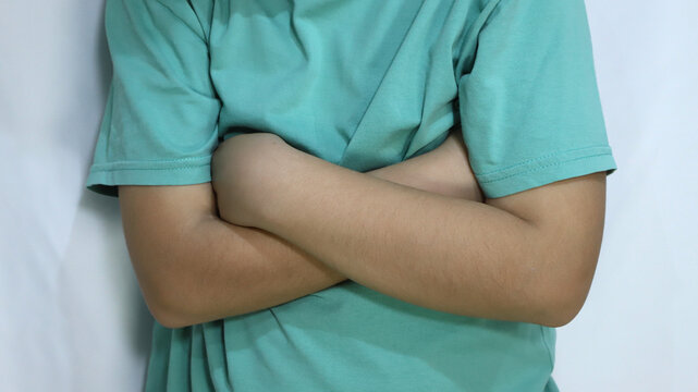 Child with arms crossed. Closeup of angry boy with arms crossed in sign of anger, whim, protest, denial. Concept of anger, bad day, denial.