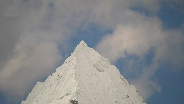 ice covered glacier of a pyramid shaped mountain at laguna paron lagoon in the high andes mountains of the cordillera blanca at huascaran, Peru, with snow covered mountain peaks on a bright sunny day.