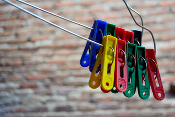 close up of colorful clothespins on a clothes hanger on a brick background