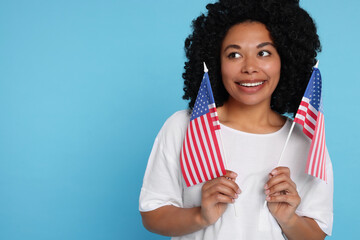 4th of July - Independence Day of USA. Happy woman with American flags on light blue background,...