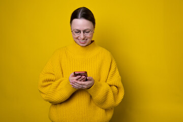 Portrait of attractive cheerful girl using device gadget app smm post isolated over bright yellow color background