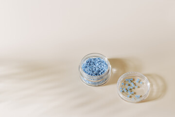 Elements for nails decor, blue stars in nail accessories box, stars for nail art in glass jar on beige background, copyspace. Creative beauty concept, pastel colors photo, visual content