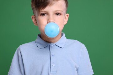 Boy blowing bubble gum on green background