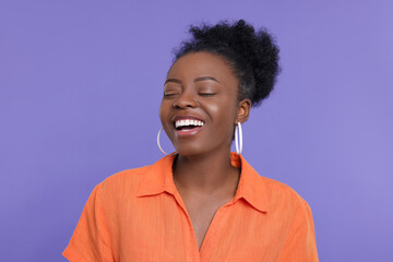 Portrait of happy young woman on purple background