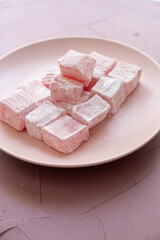 Pink Turkish delights with roses on a pink plate
