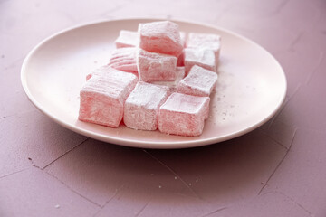 Pink Turkish delights with roses on a pink plate
