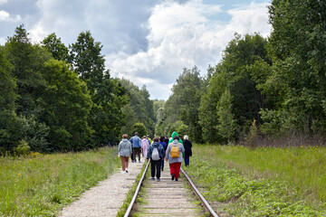 A group of emigrants moves along abandoned railway tracks in the forest