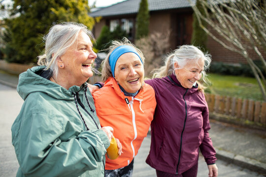 Three joyful senior women sharing a lighthearted moment during an outdoor gathering