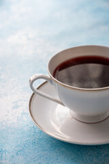 red colored tea in porcelain cup on turquoise background
