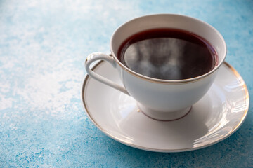 red colored tea in porcelain cup on turquoise background
