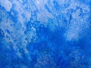 An old rusty wall with damage and stains. Blue metallic background.